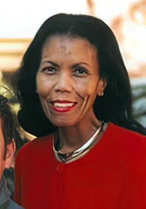 Dr. Tucker wears a red shirt and silver necklace. She is standing, looking at the camera, and smiling.