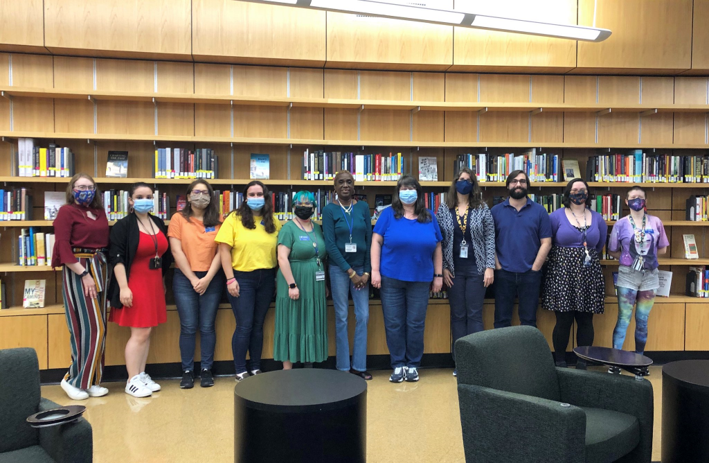 Library workers at Library West wearing red, orange, yellow, green, blue, and purple clothes to form a rainbow.