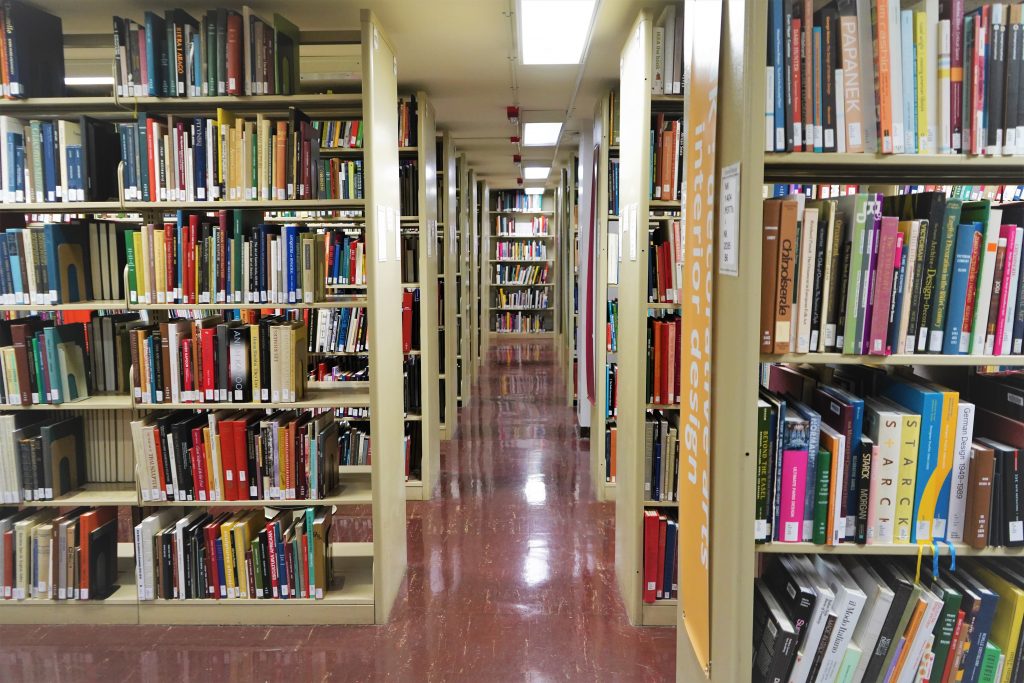 Looking down a walkway between bookshelves filled with books