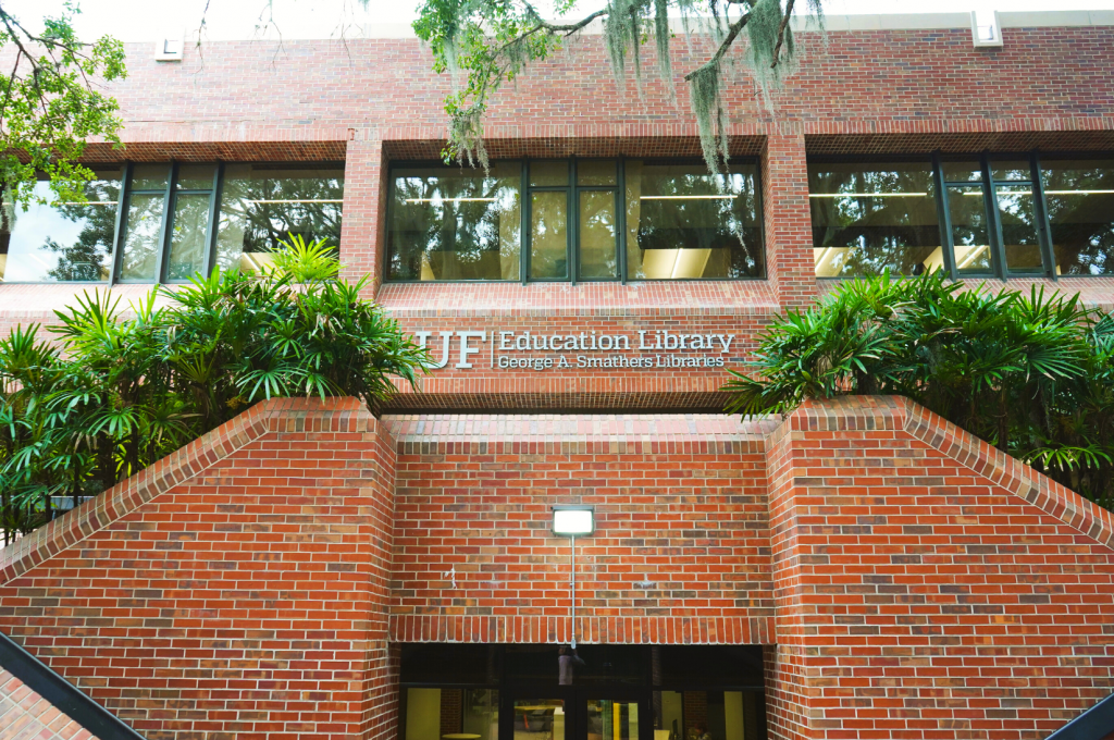 A brick building with a dual staircase leading up. The upper landing signage says "UF Education Library, George A. Smathers Libraries"