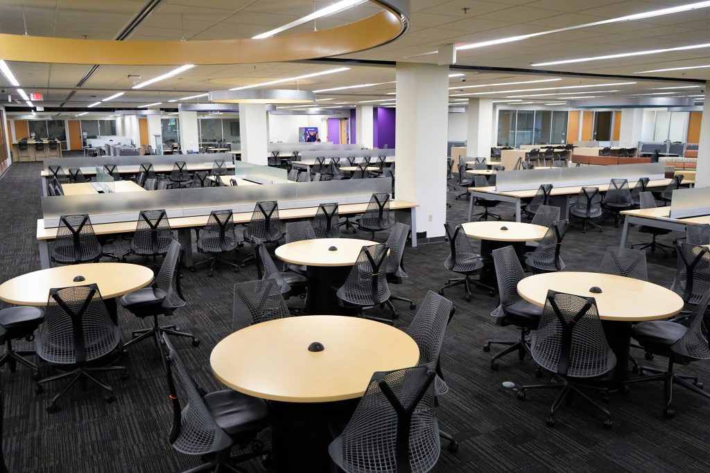 A large open space filled with round tables, long desks, and chairs