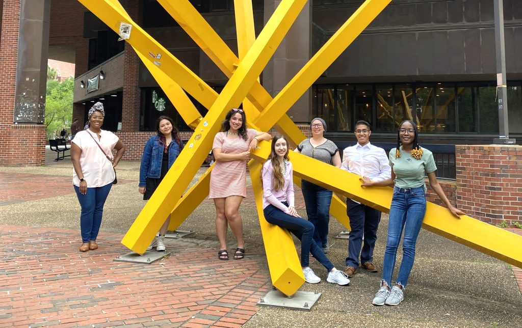 The book authors smiling at the base of the Marston "french fries," a modern sculpture made from bright yellow crisscrossed beams