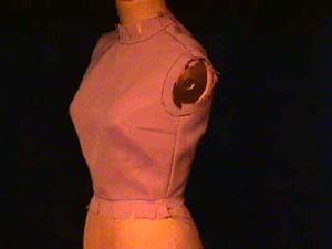 Dress form wearing a garment with darts at the side seams.
