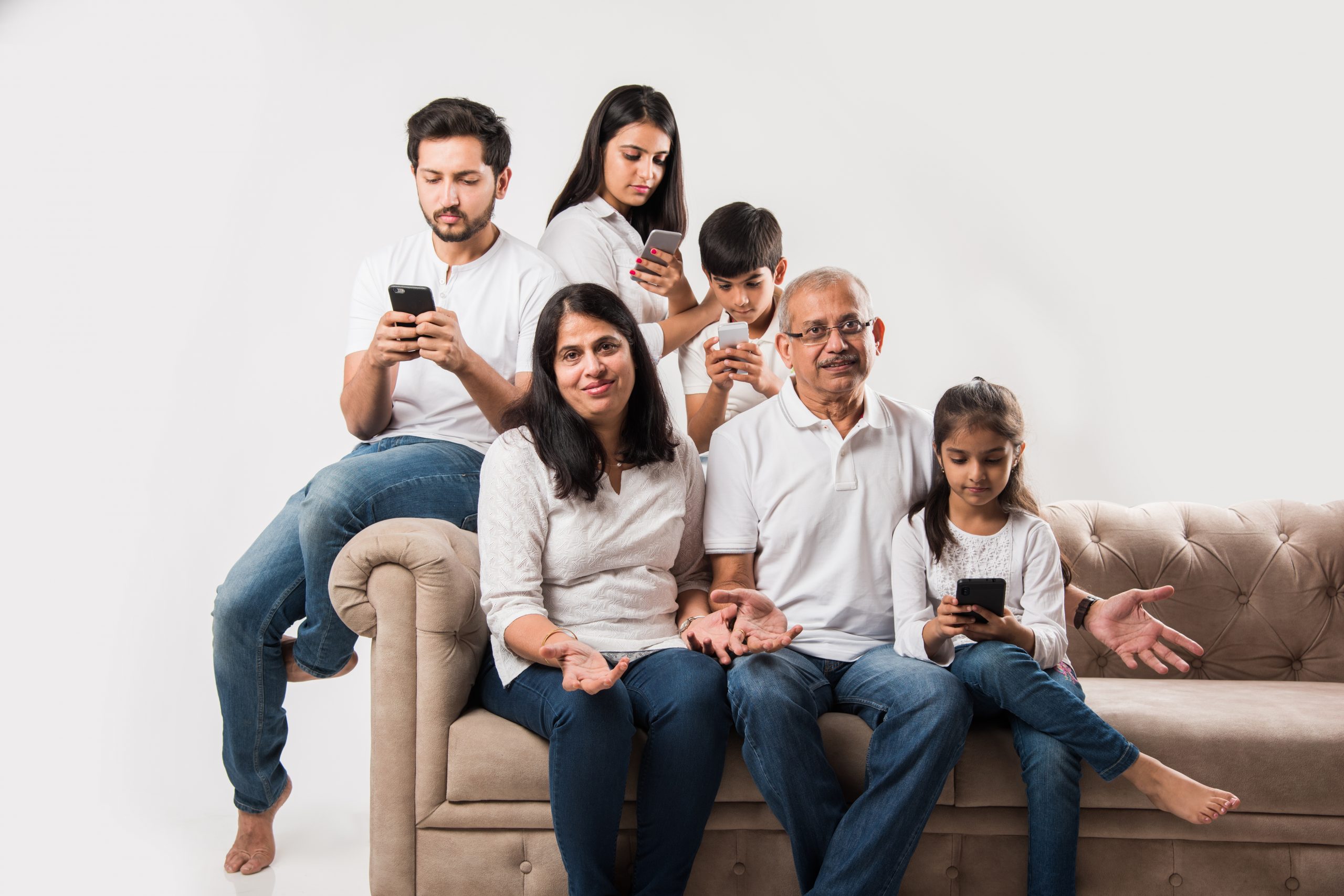 Photograph of adults who are likely parents, with two older and two younger children, with all children using mobile devices, arranged in a family portrait style