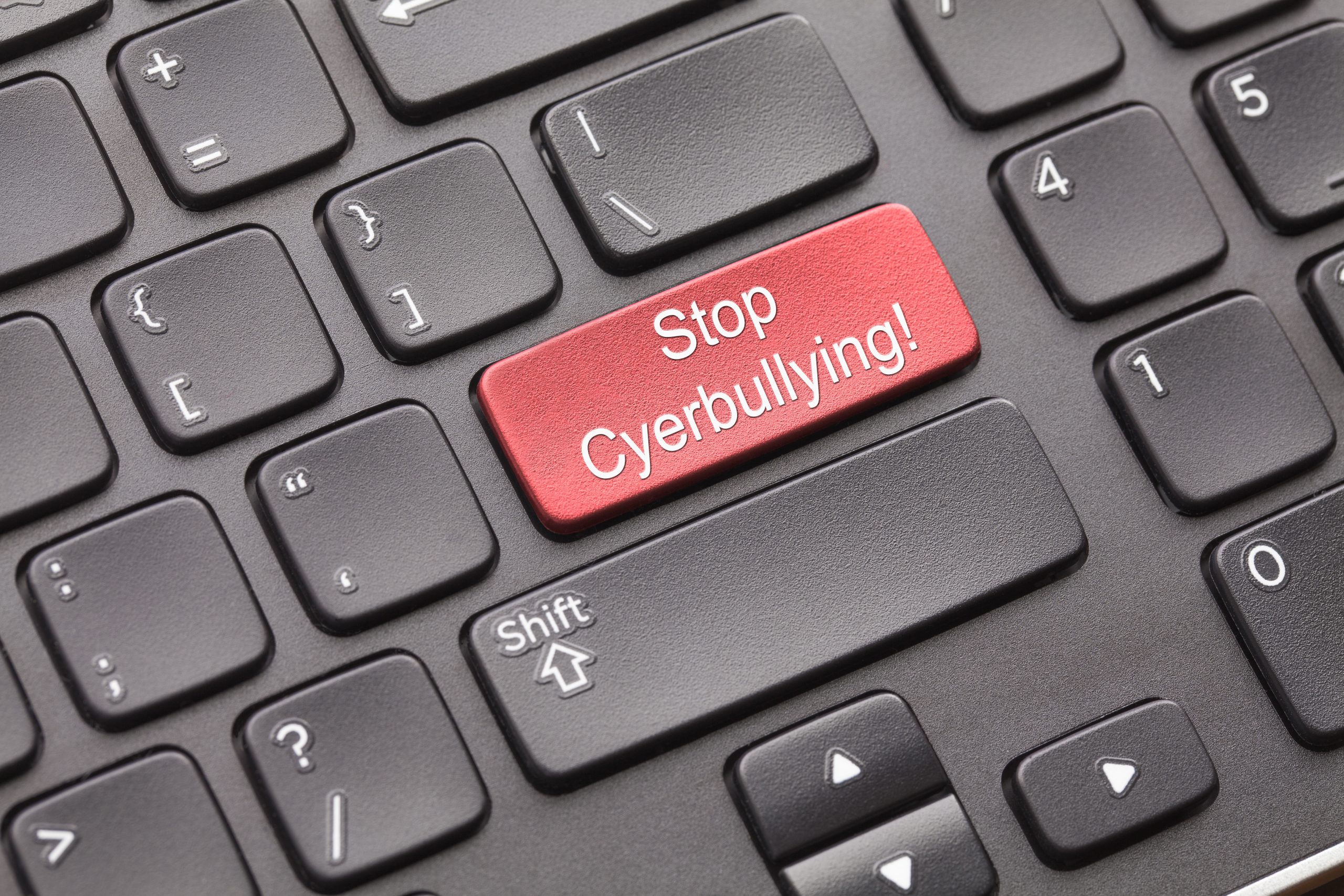 Photograph of a keyboard, with an added red key with the words Stop Cyberbullying