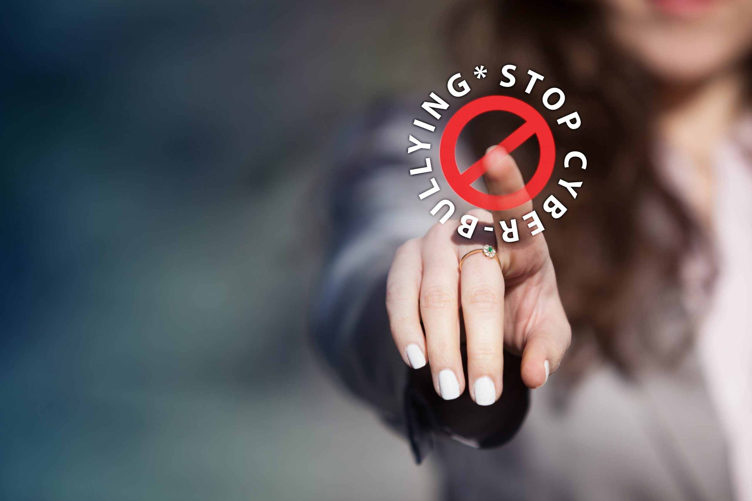 Photo of person with outstretched hand touching text and sign for stop cyber bullying