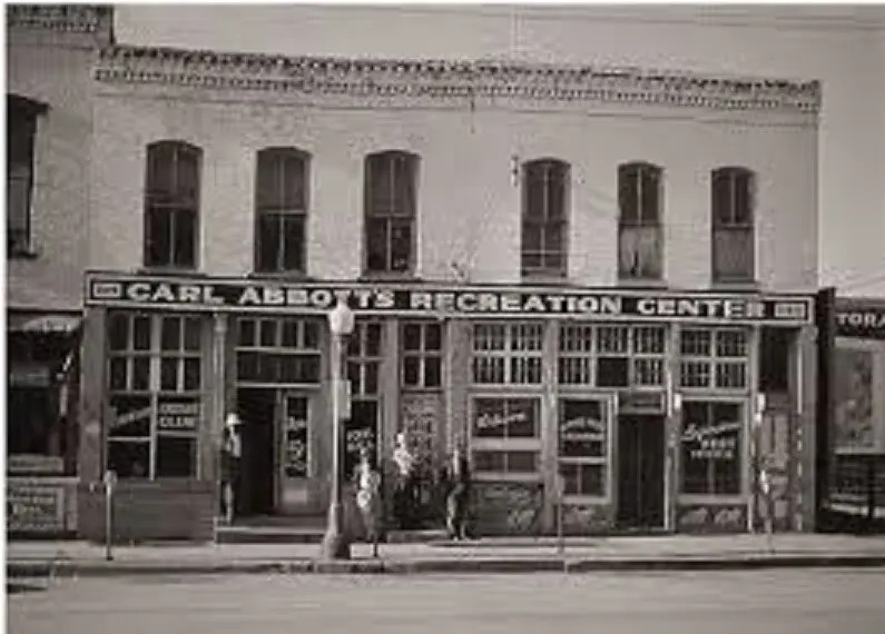 A two-story building with a long sign that reads "Carl Abbott's Recreation Center" behind a street. This building was the site of the Maple Leaf Club.