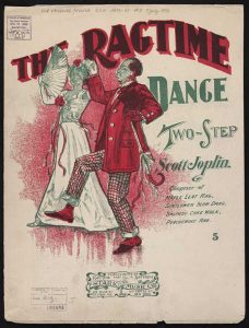 Sheet music cover, with the title "The Ragtime Dance" in large, curved lettering at the top. Slightly overlapping the title on the left is a cartoon drawing of a man and woman holding hands and stepping; the woman is holding a fan, and the man is holding a cane. Under the title on the right side are the words "Two-Step, Scott Joplin," and in smaller words under that: "Composer of Maple Leaf Rag, Sunflower Slow Drag, Swipesy Cake Walk, Peacherine Rag." At the very bottom is a stamped logo for Stark Music Co., with a bird surrounded by a ribbon.