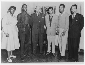 Barbara Jordan standing with five men, all from the Texas Southern University debate team. She is all the way on the left, next to her debate partner. Dr. Freeman, their debate coach, is near the middle of the line.