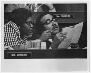 Close-up of Barbara Jordan and Charles B. Rangel looking over a copy of the Constitution during the Nixon-Watergate impeachment hearings at a long table.