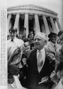 Watergate special prosecutor, Leon Jaworski, outside the Supreme Court building after a hearing in July 1974. He is surrounded by a crowd of people.