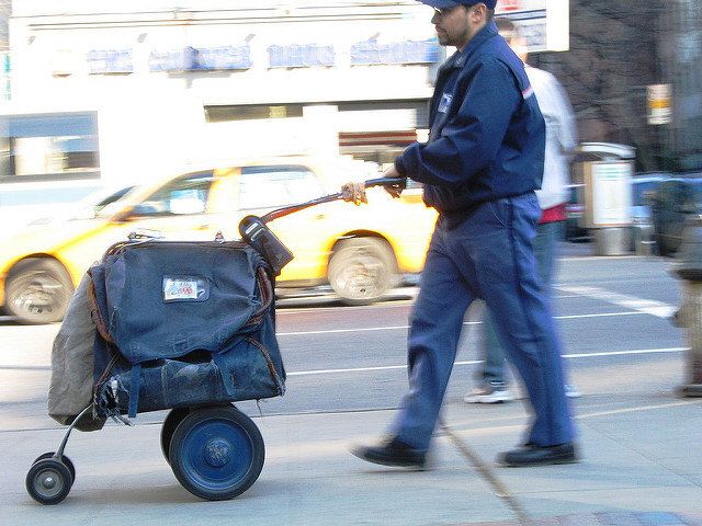 Mailman pushing a cart full of mail