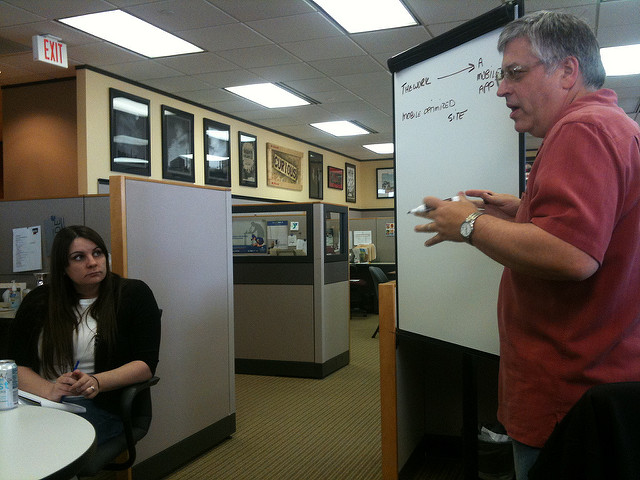 A man tutoring a woman while using a dry-erase board