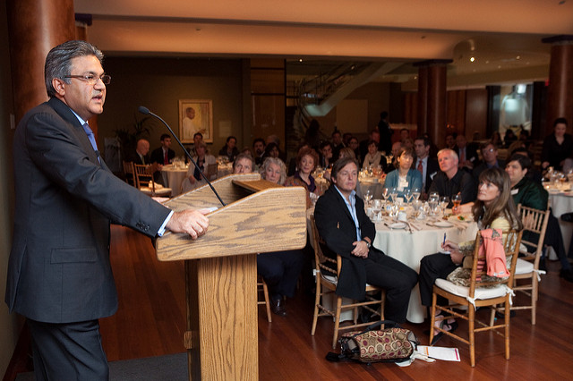 A man giving a speech at a podium during a fancy reception