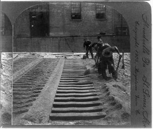 People digging in front of brick building