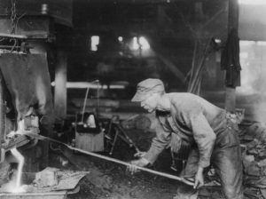 Man using long stick to tap steel