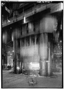 Grayscale photograph of facility with press, somewhat out of focus