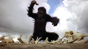 Primate smashing bones in front of blue sky and clouds