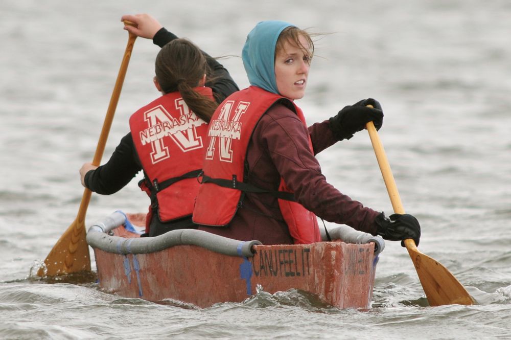 Two rowers in bright orange life vests with University of Nebraska logo in concrete canoe