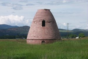 Large kiln surrounded by grass with mountains and sky in background