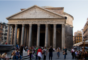 Exterior view of front of Pantheon at dusk with crowd of people and fountain in foreground