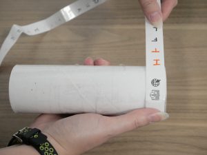 Two hands wrapping a coded strip of paper around a cylinder