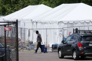 A shelter staff member is walking in front of 2 large, white tents.