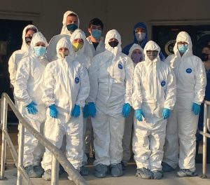 Shelter staff team of 11 people outside wearing full coverage white Tyvek suits with hoods and grey foot covers