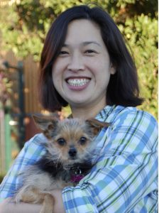 Headshot portrait of Dr. Kamiya posing with a small, wire-haired dog