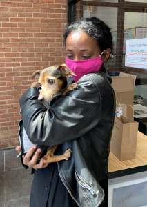Saron is wearing a facemask while holding her little dog Rita outside of the clinic.