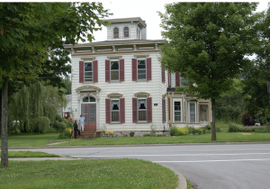 Color photograph of a two story building with red-shuttered windows.