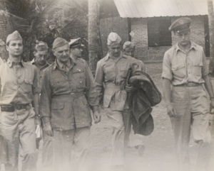 Black and white photograph of men, who are walking in military uniforms.