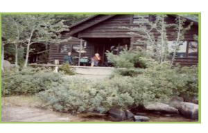 Color photograph of Dorothy and Sam sitting on the porch of a log cabin.