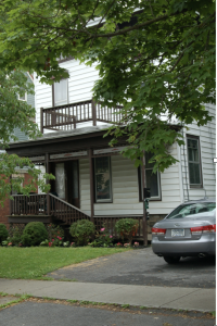 Color photograph of a two-story building with a porch on the first floor and a deck on the second.