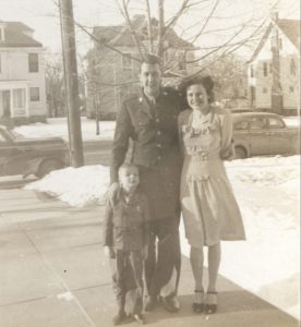 Black and white photograph of Bill and Dorrie, standing behind Penny. Bill has his hand on Penny's shoulder.