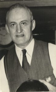 Black and white photograph of Eugene, who is looking at the camera and smiling.