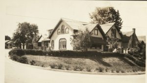 Sepia photograph of the MacDonald home behind a long curved driveway, which is edged in neat hedging.