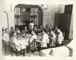 Black and white photograph of officers sitting at a table with plates of food.